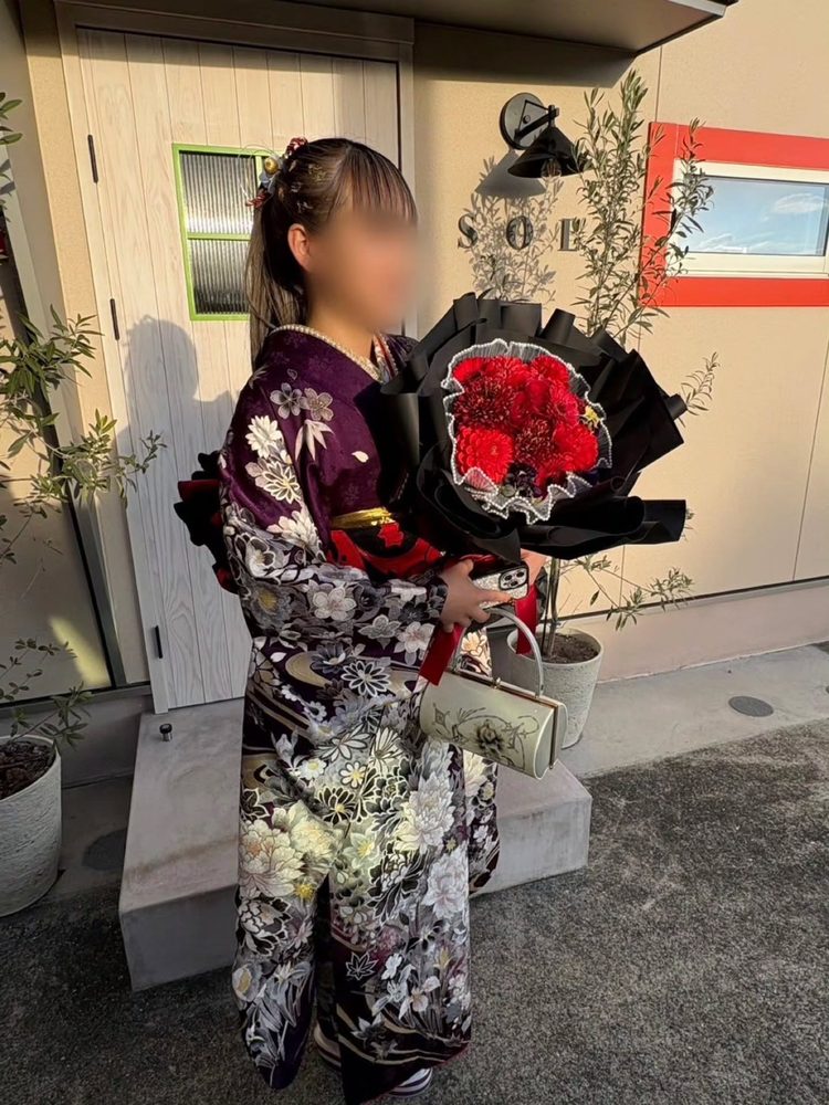紫地に白黒の花の振袖でお花を持つお客様（成人式）